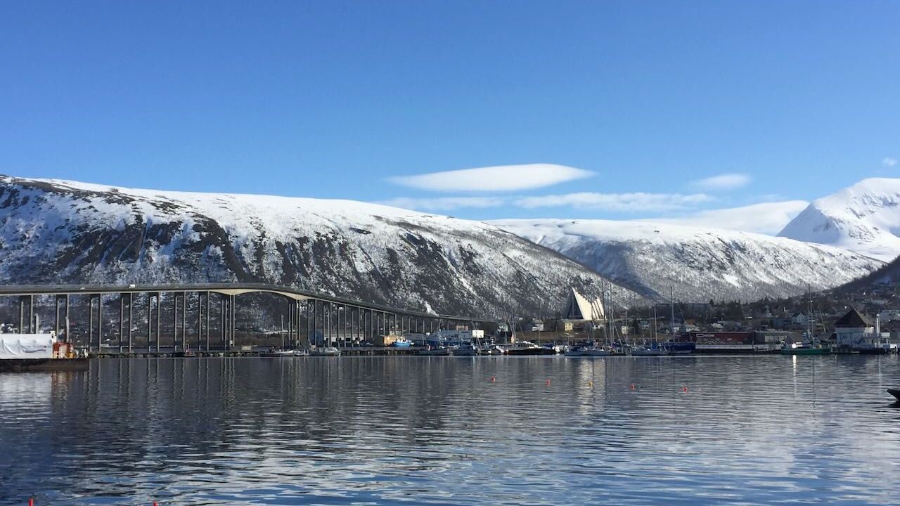 A bridge in Tromso Norway with snow covered hills behind it