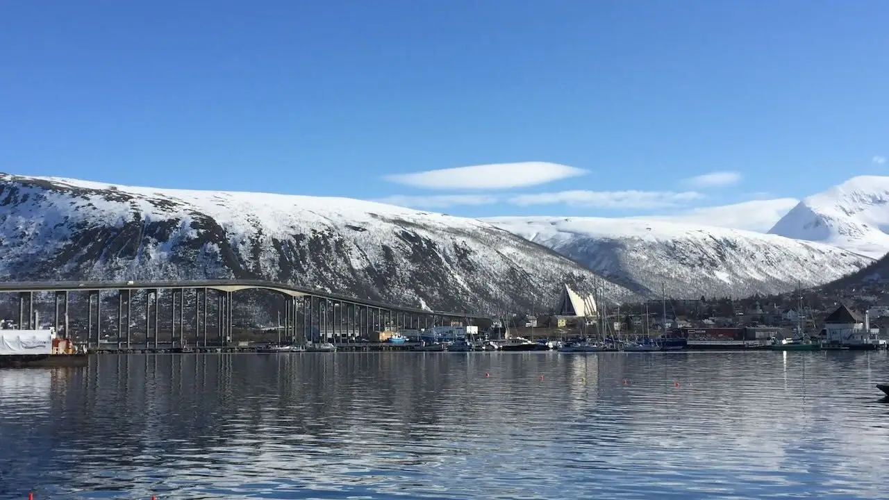 A bridge in Tromso Norway with snow covered hills behind it